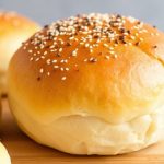 Pillowy golden Hawaiian rolls cooling on a wooden board, butter melting into soft crumb.
