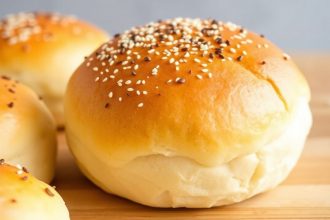 Pillowy golden Hawaiian rolls cooling on a wooden board, butter melting into soft crumb.