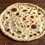 Stack of freshly baked Injera with airy, spongy texture on a woven platter