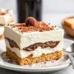 Creamy mascarpone tiramisu slice dusted with cocoa on a vintage dessert plate.