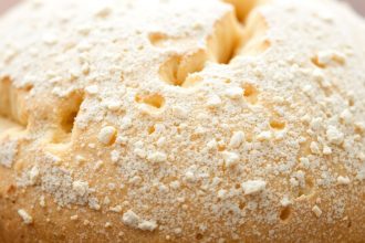 رغيف خبز بقشرة باهتة على لوح خبز، أدوات فرنية في الخلفية