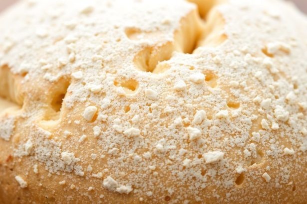 رغيف خبز بقشرة باهتة على لوح خبز، أدوات فرنية في الخلفية