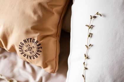 وسادة أحلام عُشبية محشوة بأعشاب مهدئة بجانب كتاب وشمعة