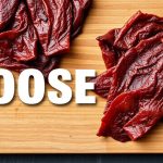 شرائح لحم أوزة مجففة منزلية متبلة على لوح تقطيع خشبي