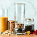 كتب وصفات لخلطات حرفية، أوعية مكونات ملونة وخلاط يدوي على الطاولة