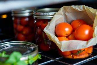 طماطم تُعلّب في فرن مع علامة خطر، وبدائل تعقيم آمنة بجانبها