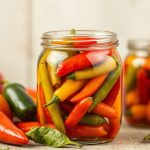 برطمان فلفل حار مخلل أحمر وأخضر على طاولة خشبية