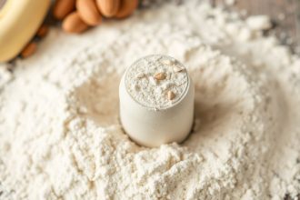 محضّر طعام يطحن مكسرات إلى دقيق ناعم في وعاء زجاجي