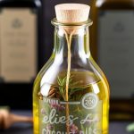 زجاجات زيوت منقوعة بالأعشاب الطازجة وأوراق ريحان على طاولة