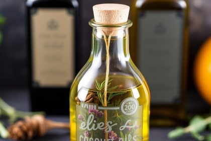 زجاجات زيوت منقوعة بالأعشاب الطازجة وأوراق ريحان على طاولة